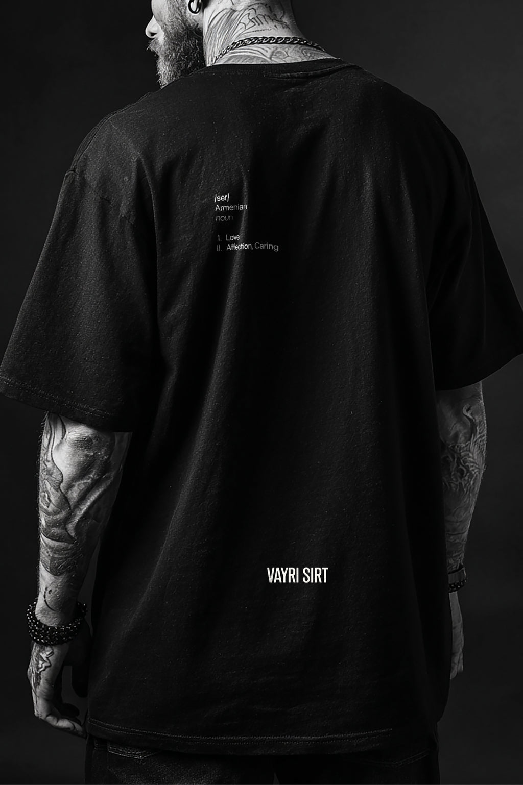 Person wearing a black t-shirt with text on the back against a dark background