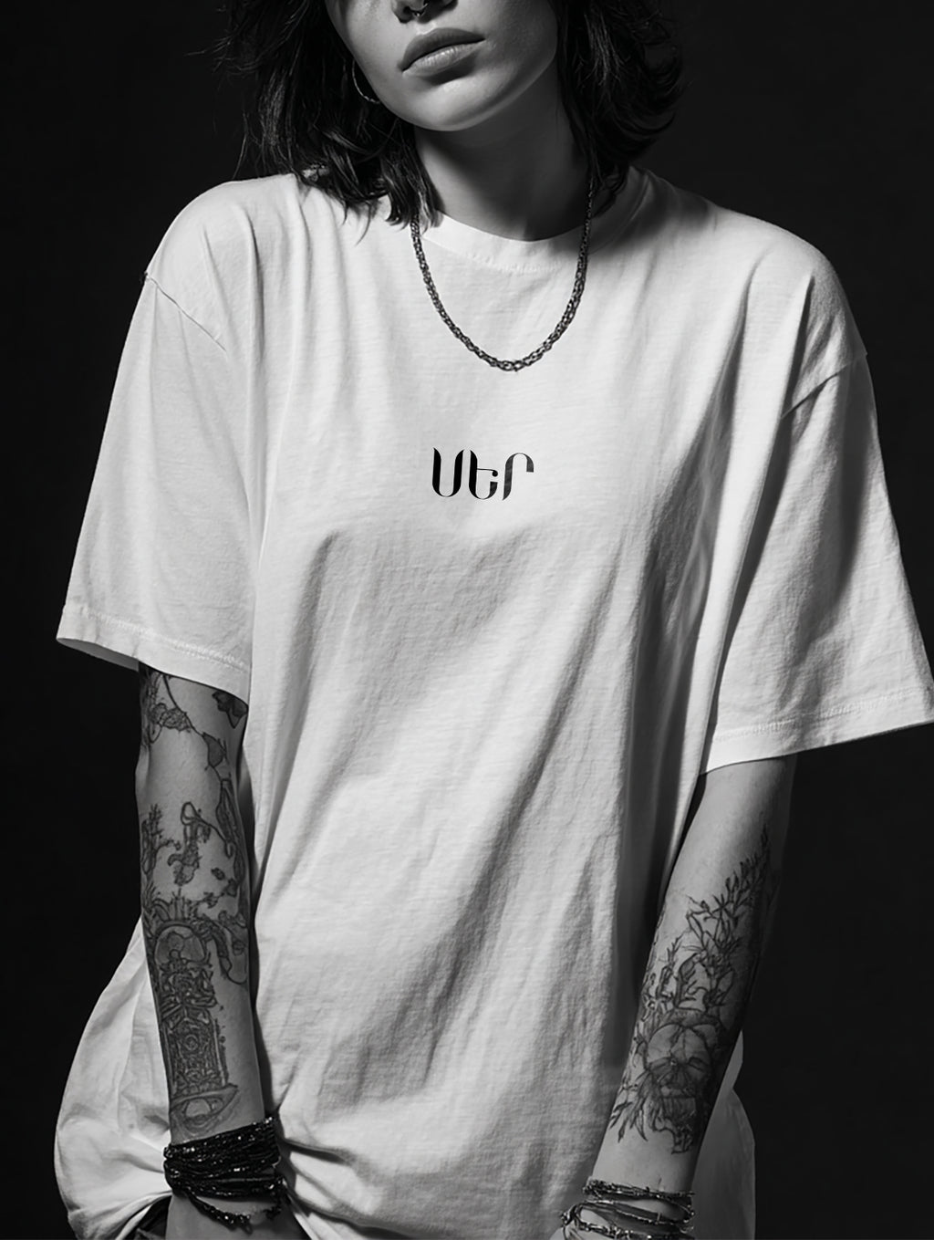 Person wearing a white t-shirt with 'ՍԵՐ' logo against a black background