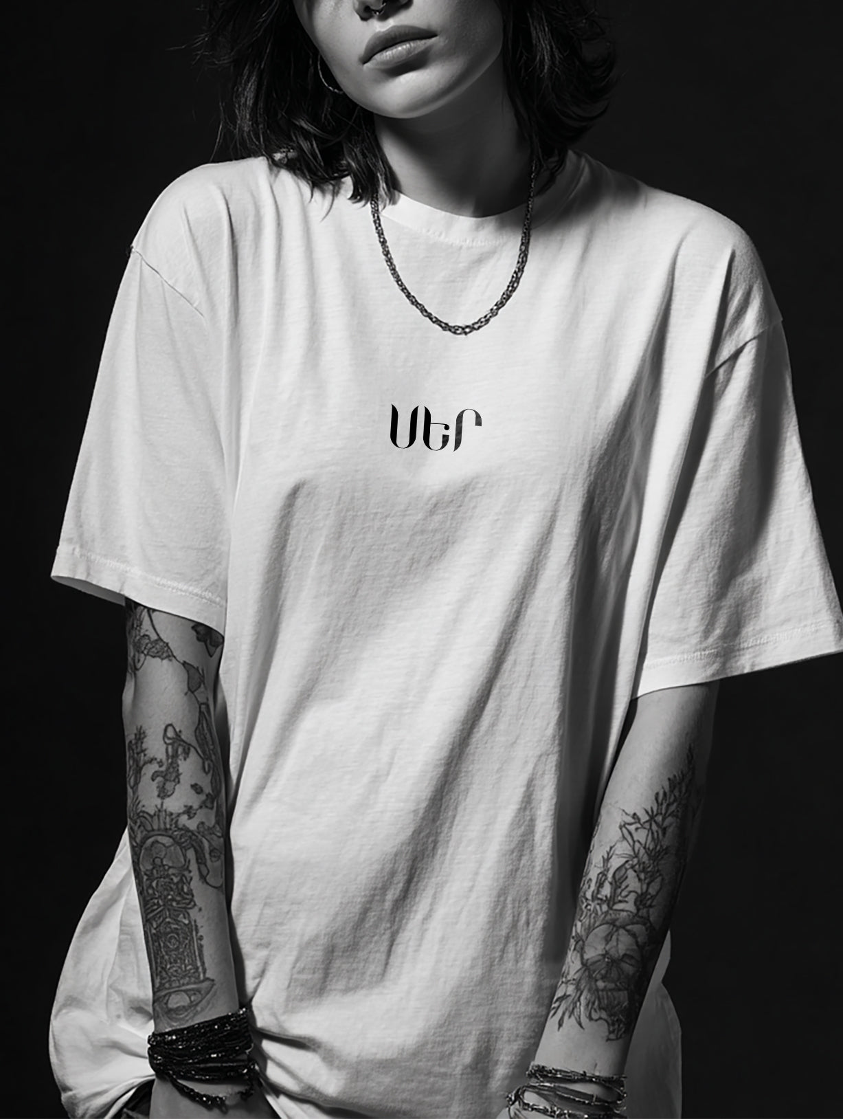 Person wearing a white t-shirt with 'ՍԵՐ' logo against a black background